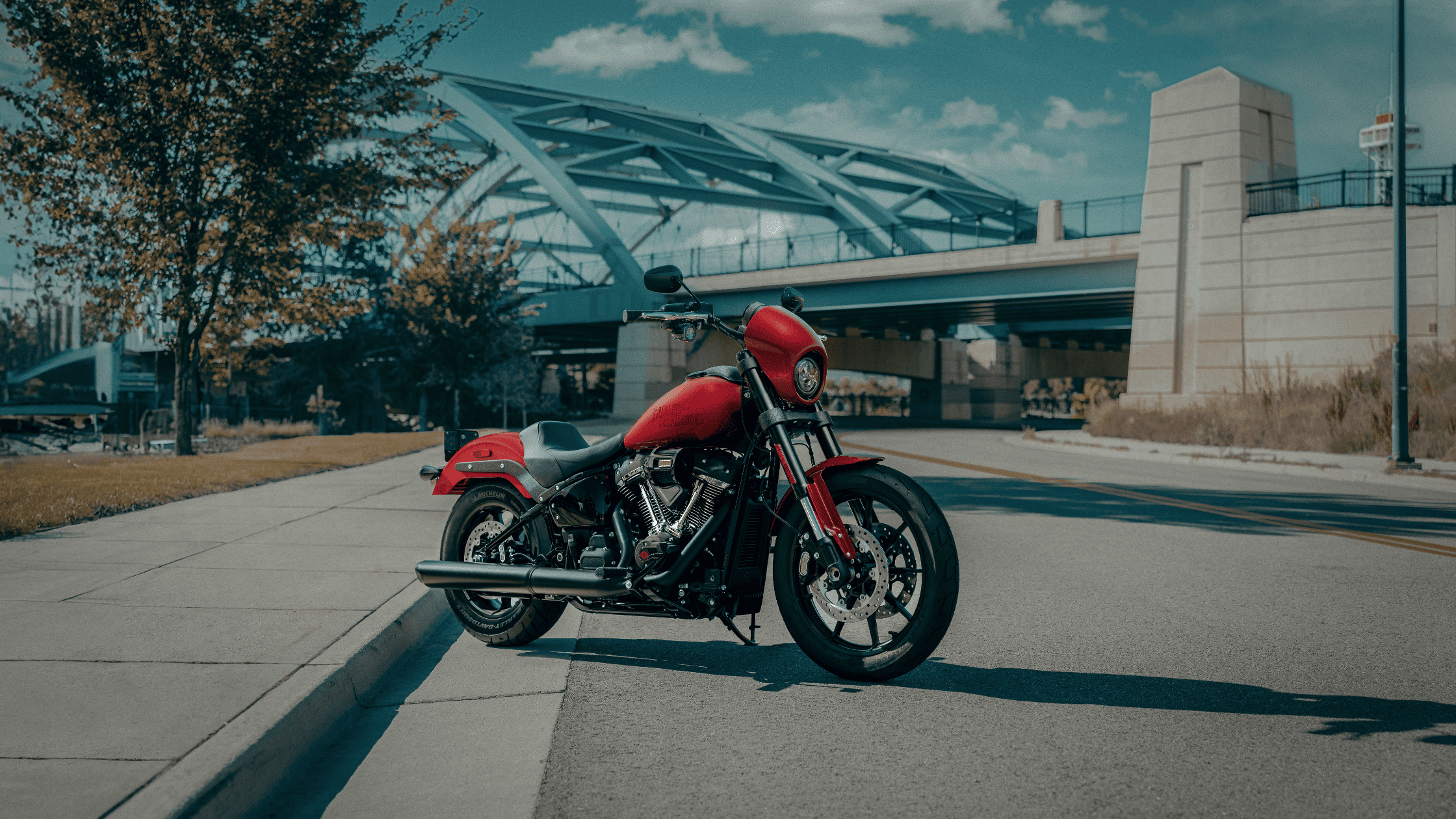 2025 Harley-Davidson® Low Rider® S in red parked by modern bridge on a clear day