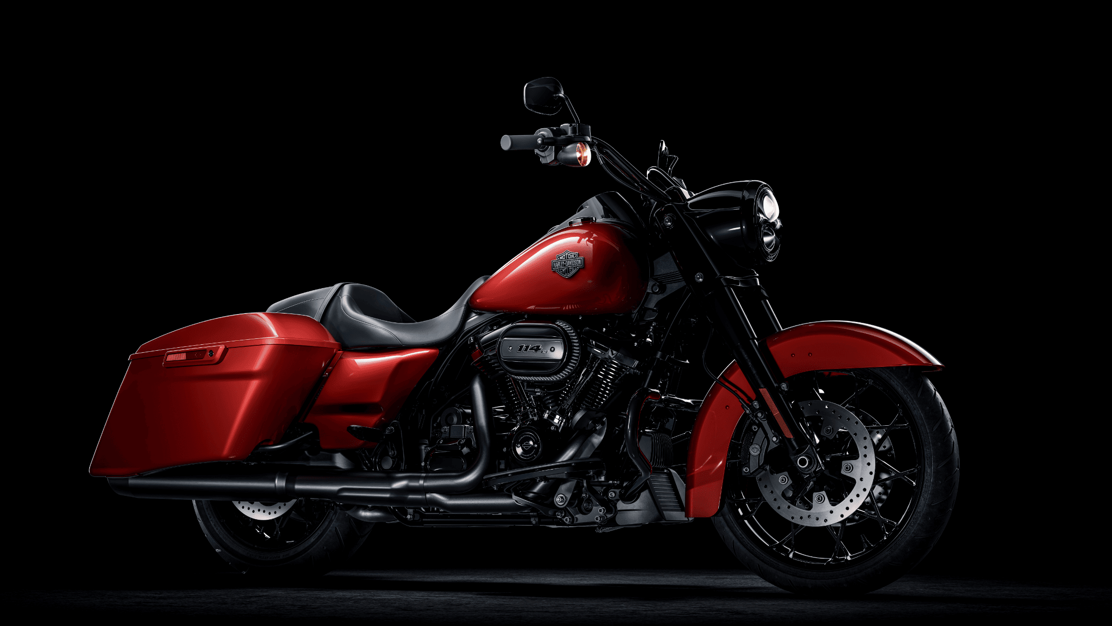 Side view of a 2025 Harley-Davidson Road King Special in red with blacked-out engine and trim, showcased against a black studio background.