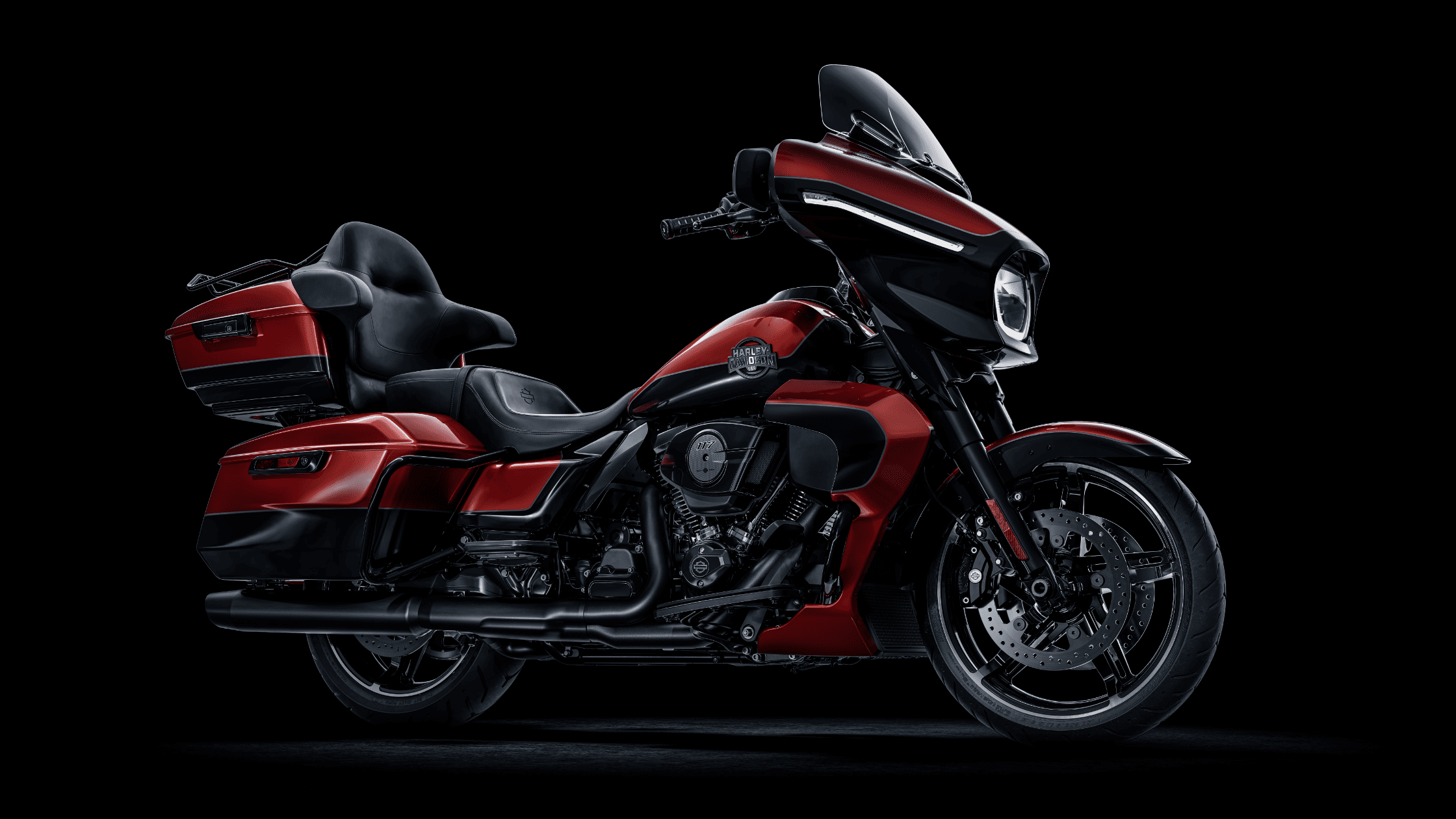 A 2025 Harley-Davidson Street Glide Ultra B in a striking red and black color scheme, featuring a large front fairing with an LED headlight, saddlebags, and a top case for touring.